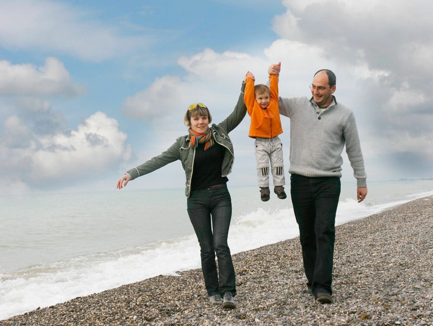 A man, woman and child walking on the beach.