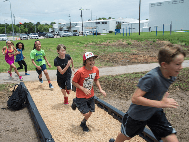 A group of kids running on the sand.