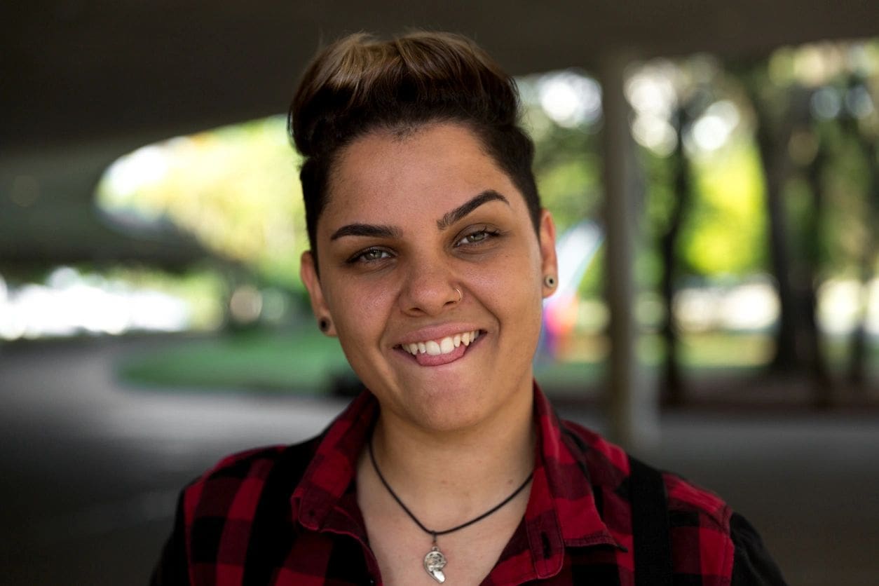 A woman with short hair wearing a red and black shirt.