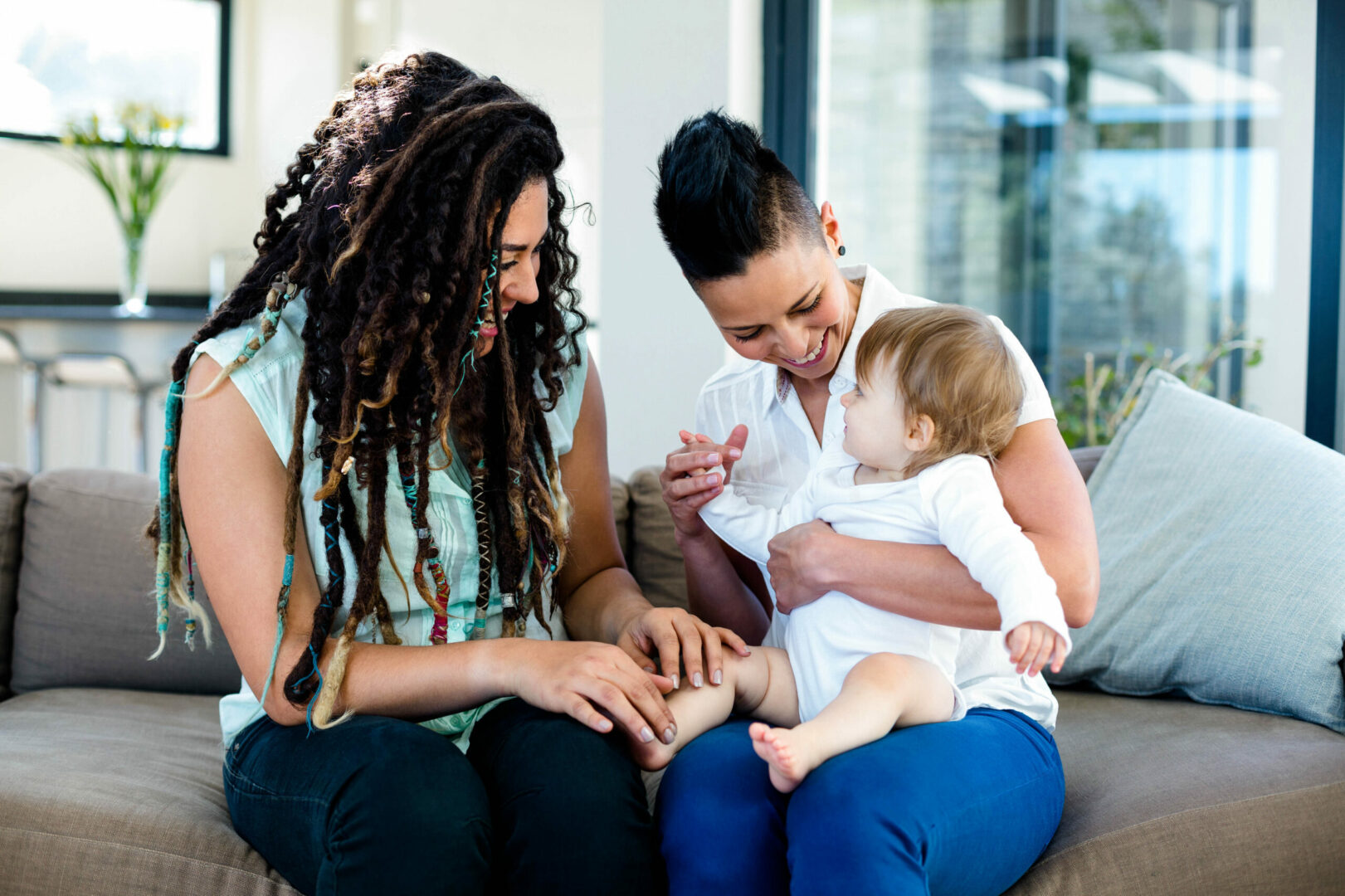 Two women and a baby sitting on the ground.