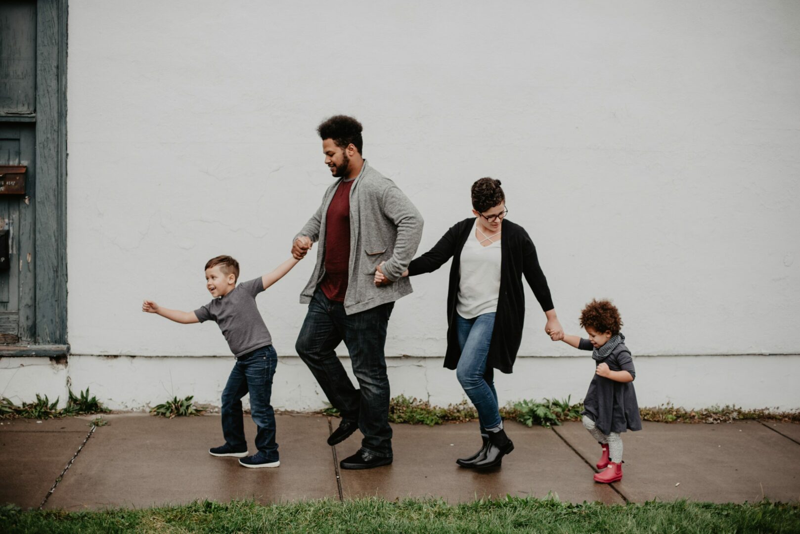 A family walking down the sidewalk holding hands.